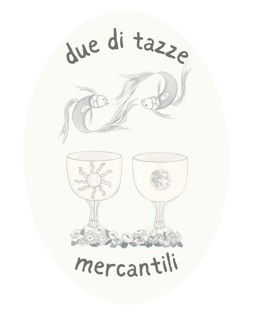 A circular logo or label design with the Italian text 'due di tazze' at the top and 'mercantili' at the bottom, surrounding a central illustration of two fish facing each other above two wine glasses decorated with a sun and moon motif.